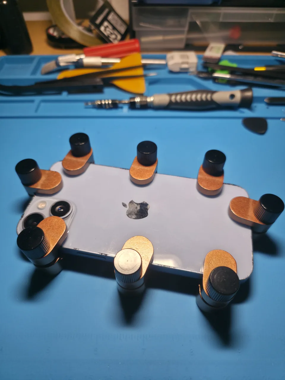 iPhone-Rückseite mit Halteklemmen auf dem Werkstatttisch